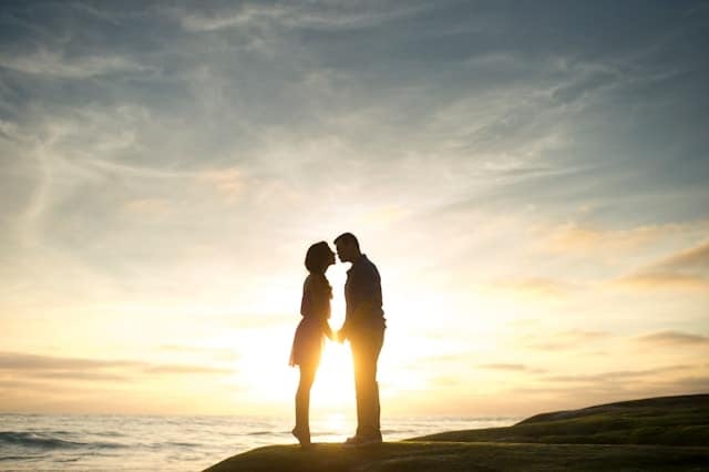 結婚 焦り 海岸で手を取り合い向き合う男女のカップル。